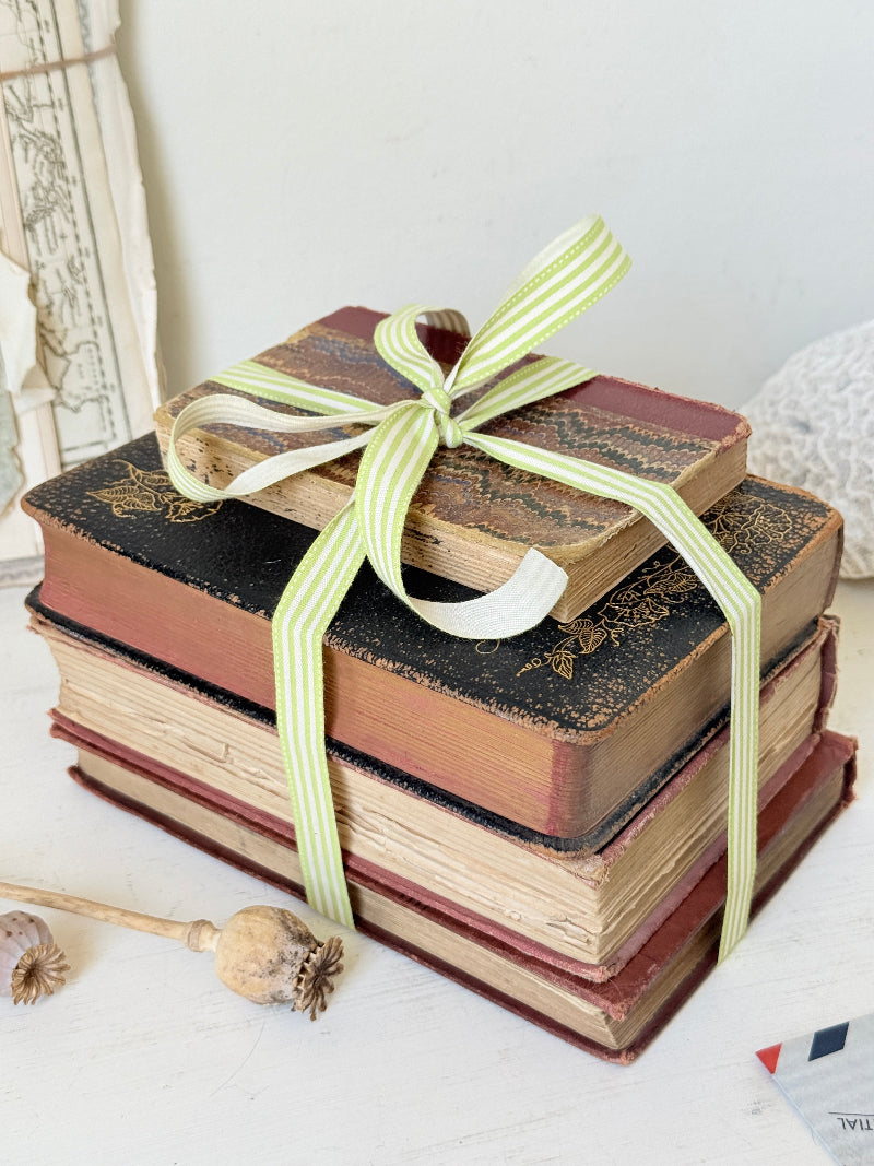 Vintage decorative book bundle with red burgundy cream and green hardback covers tied with green stripe ribbon for interior styling