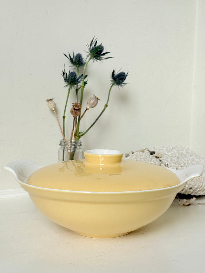 Vintage Poole Pottery lidded serving dish in soft yellow glaze with side handles, photographed on a white surface