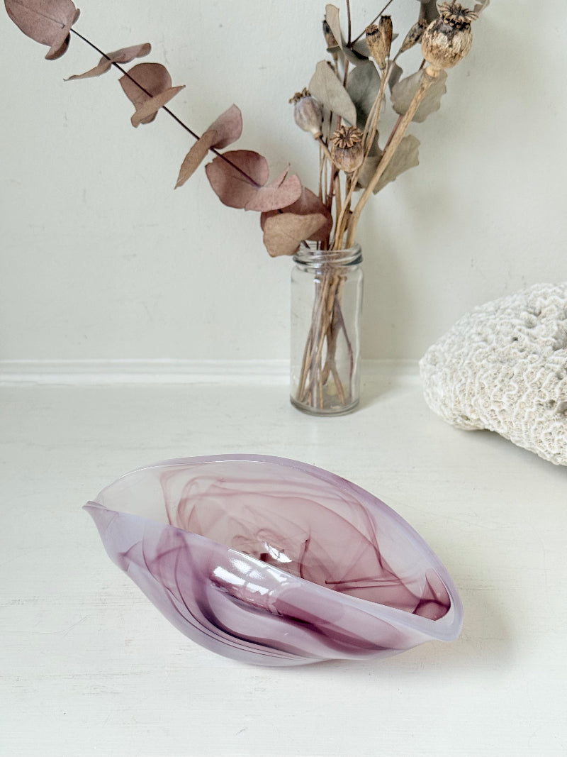 Vintage clam shaped Sowerby glass bowl in lilac purple swirl photographed on a white surface