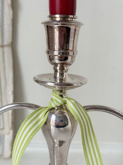 Silver plate three light candelabra with curved arms and domed base holding red taper candles