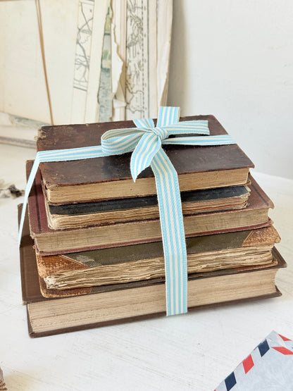 Vintage decorative brown book bundle with aged hardback covers tied with blue stripe ribbon for bookshelf and table styling