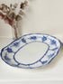 Antique oval blue and white platter with floral border photographed on a white surface