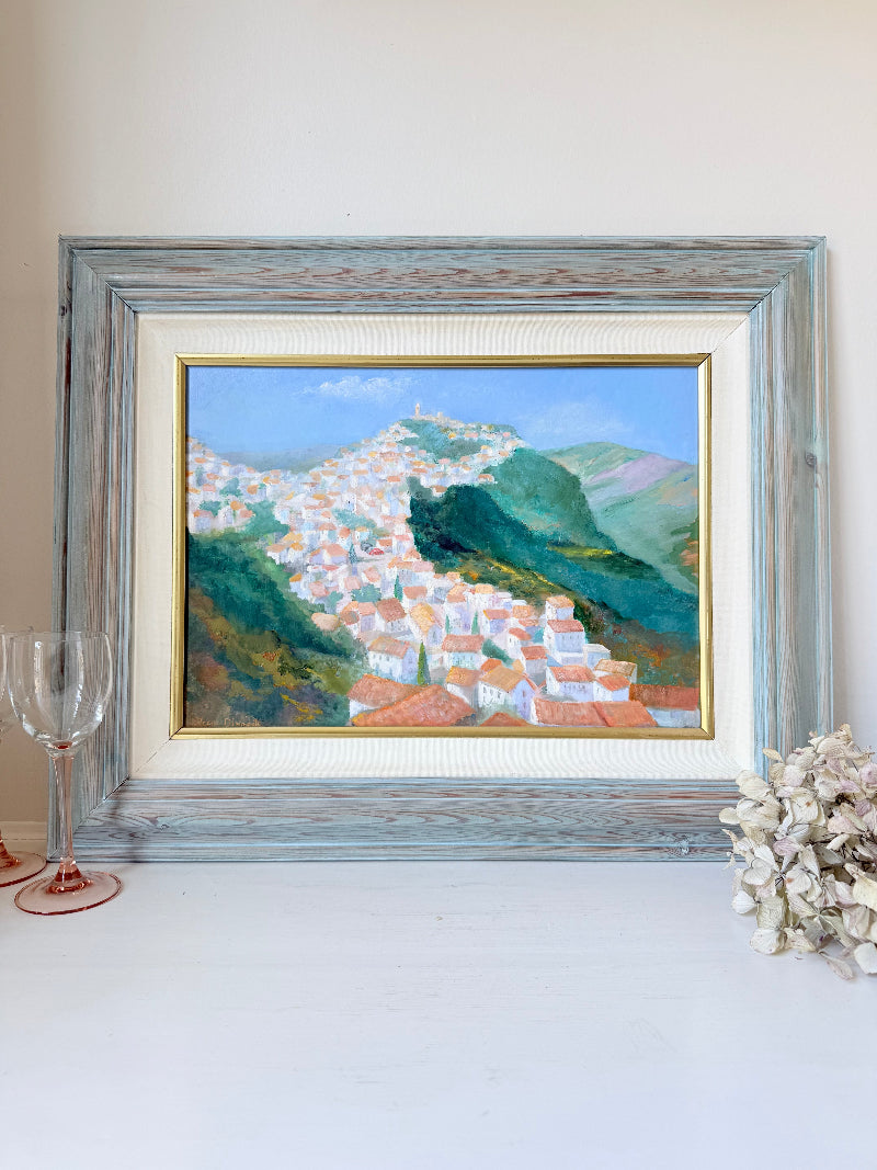 Framed oil painting of Costa del Sol with whitewashed hillside towns, photographed on a white surface