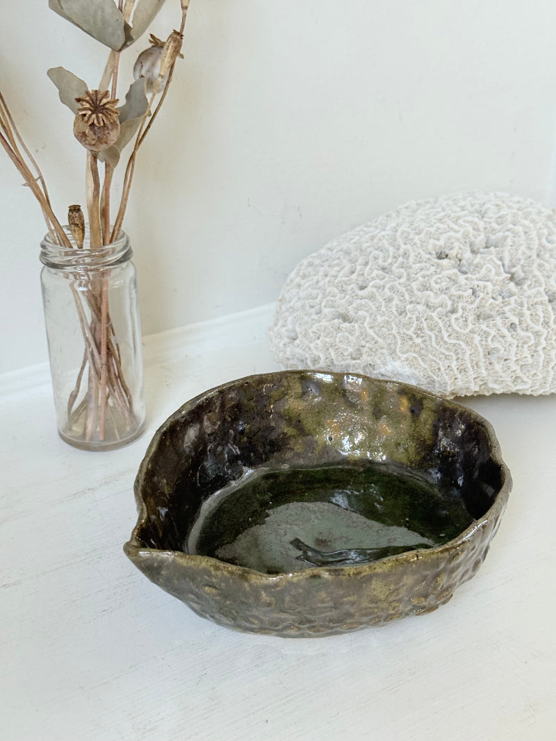 Studio pottery olive bowl with green and charcoal glaze, photographed on a white surface