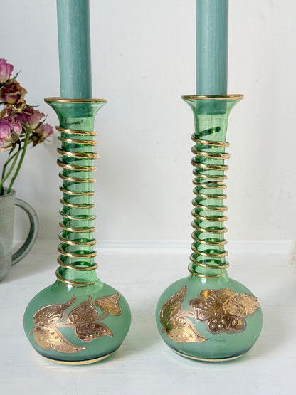 Pair of vintage green glass candlesticks with gold detail and spiral stems styled with blue taper candles on white surface