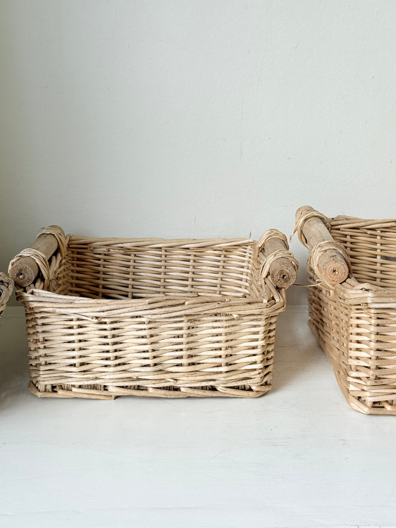 Set of three vintage woven willow baskets in natural tones photographed on a white surface
