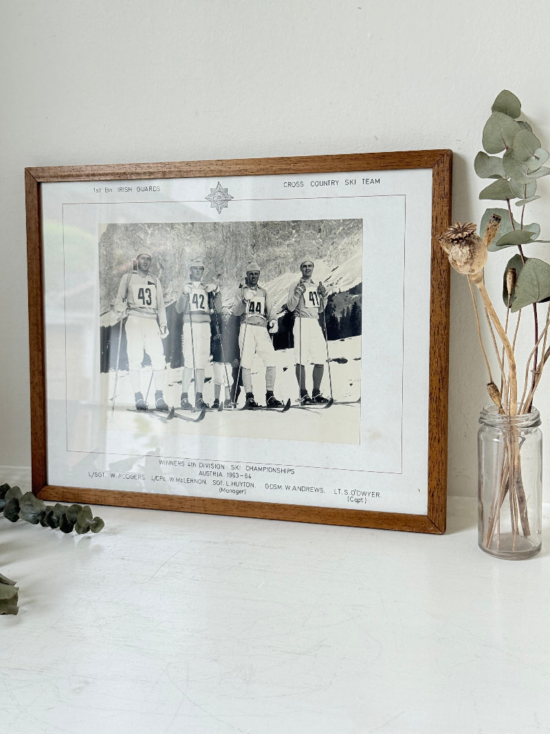 Vintage black and white framed photograph of the 1st Battalion Irish Guards Ski Team, 1963–64, posed in full ski gear against the Austrian Alps.
