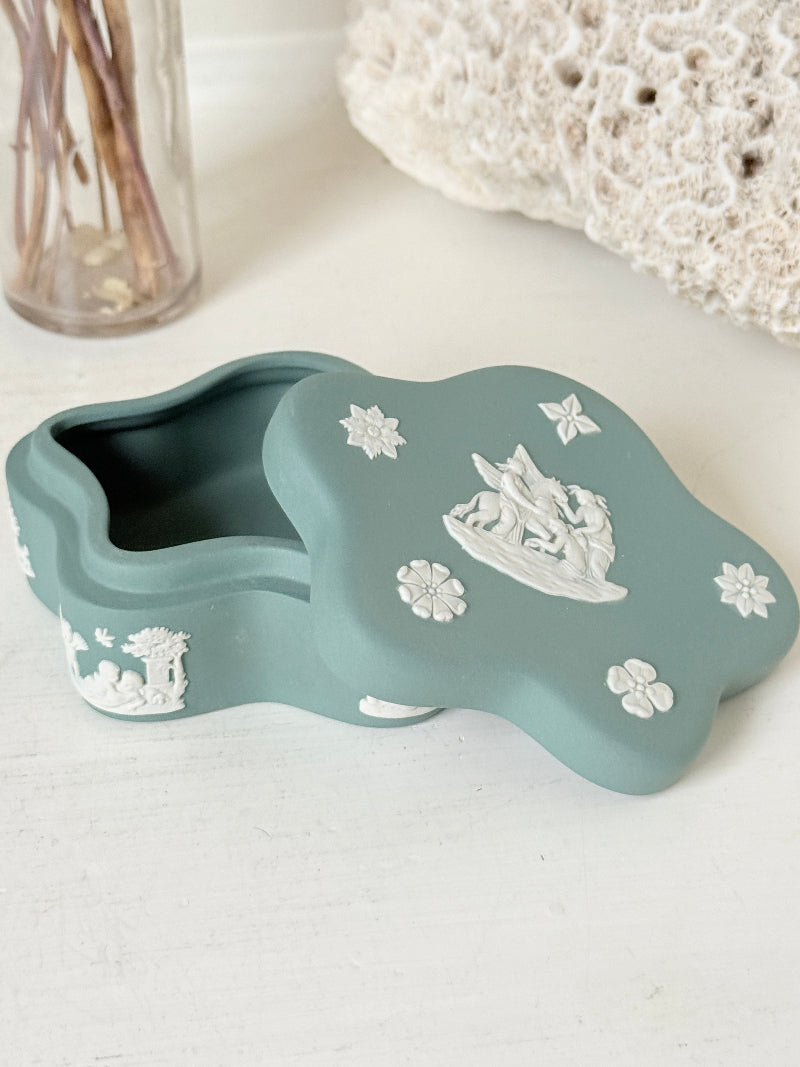 Vintage Wedgwood Jasperware teal green lidded trinket box in a quatrefoil shape, decorated with white neoclassical figures and florets, styled with dried stems.