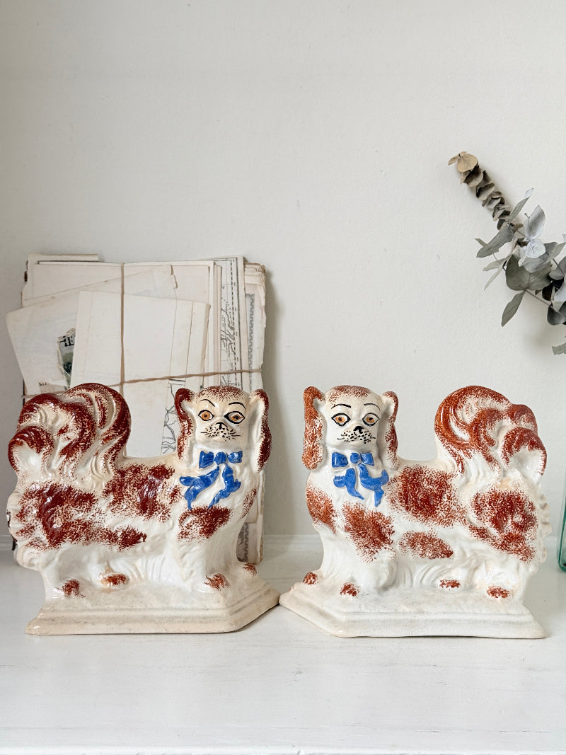 Pair of antique standing Staffordshire Pekingese dogs in rust red and white with blue painted bows