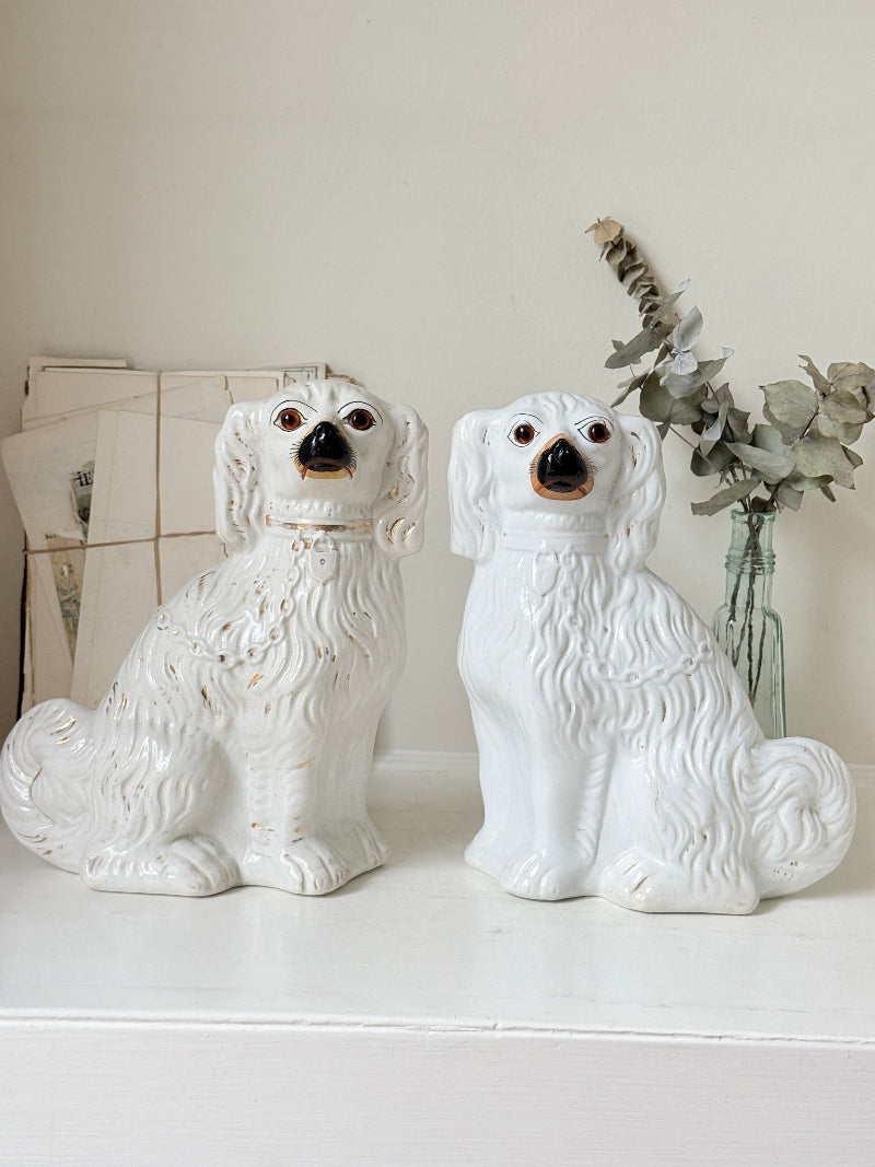 Near pair of antique white Staffordshire spaniel mantel dogs with glass eyes and worn gilt collars