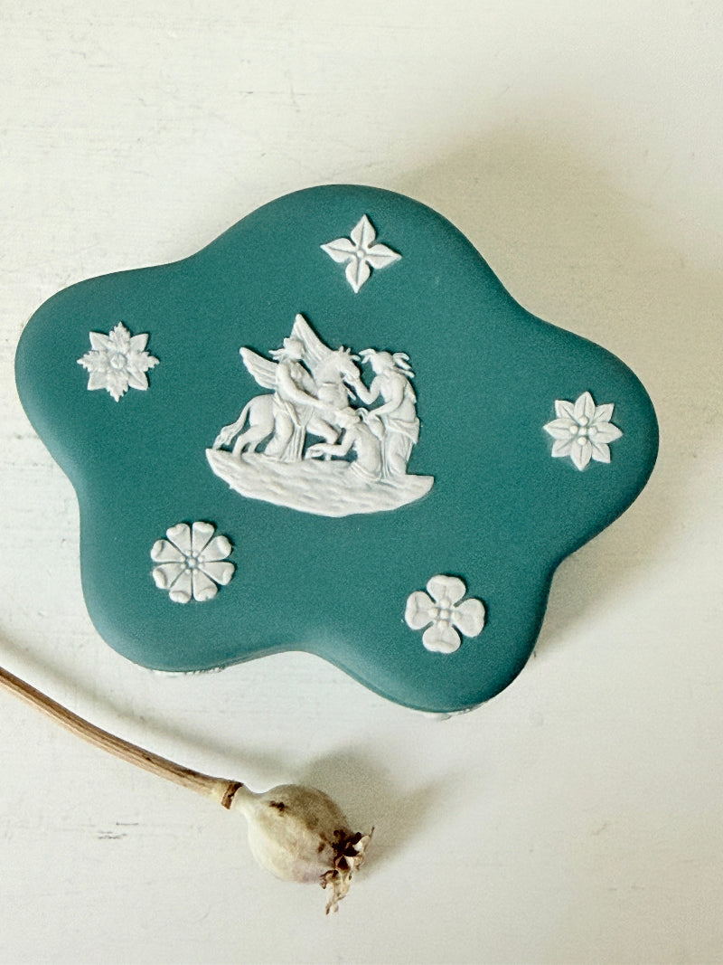 Vintage Wedgwood Jasperware teal green lidded trinket box in a quatrefoil shape, decorated with white neoclassical figures and florets, styled with dried stems.
