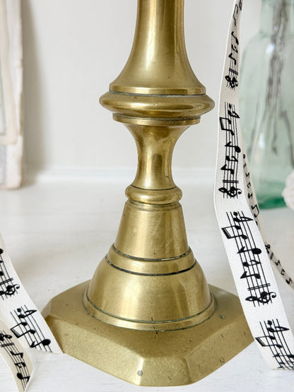 Pair of antique brass candlesticks with turned baluster stems and stepped bases holding coral tapers