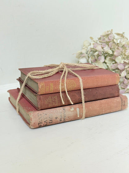 Bundle of three vintage books in worn rose and blush tones tied with natural twine, photographed on a white surface