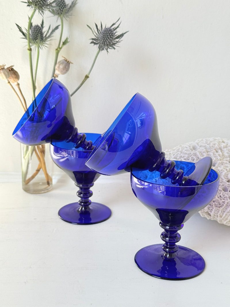 Set of four vintage cobalt blue cocktail glasses with stepped stems, photographed on a white surface