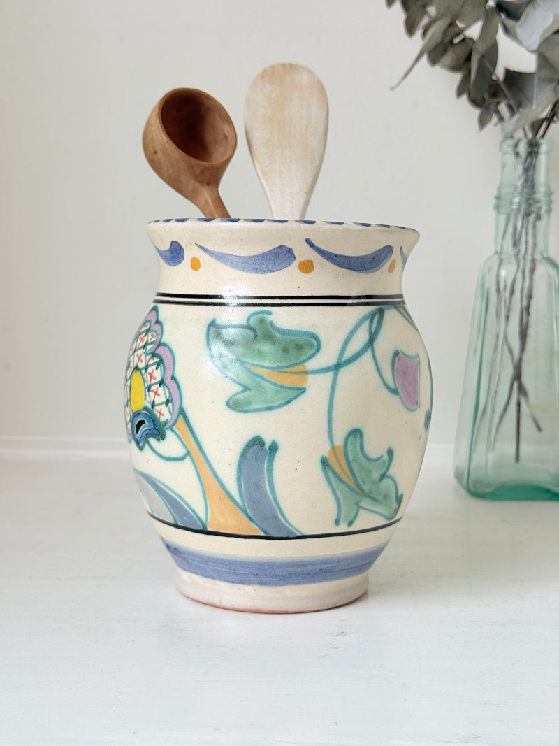 Hand painted floral pottery vase in blue and green on cream, photographed on a white surface