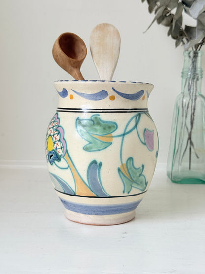 Hand painted floral pottery vase in blue and green on cream, photographed on a white surface
