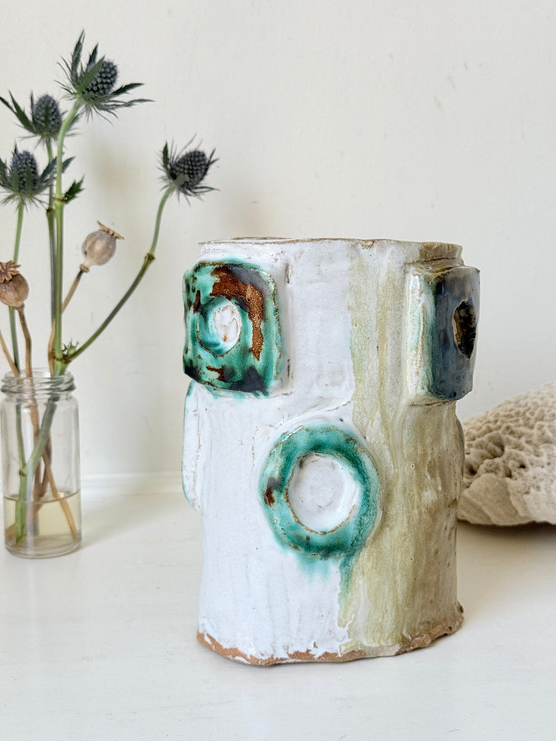 Vintage studio pottery vase in white, ochre and turquoise with abstract applied decoration, photographed on a white surface