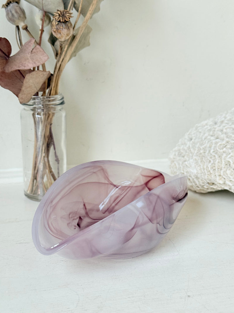 Vintage clam shaped Sowerby glass bowl in lilac purple swirl photographed on a white surface