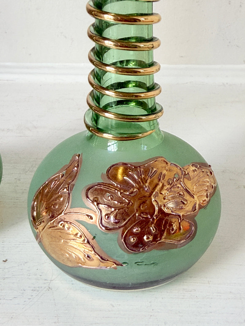 Pair of vintage green glass candlesticks with gold detail and spiral stems styled with blue taper candles on white surface