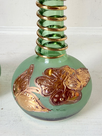 Pair of vintage green glass candlesticks with gold detail and spiral stems styled with blue taper candles on white surface