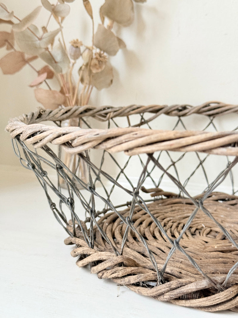 Vintage wicker and wire basket with woven base photographed on a white surface