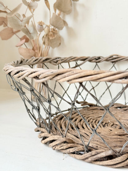 Vintage wicker and wire basket with woven base photographed on a white surface