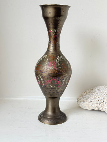 Vintage Indian engraved brass vase with enamel floral decoration and aged patina styled with dried stems on white surface
