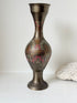 Vintage Indian engraved brass vase with enamel floral decoration and aged patina styled with dried stems on white surface
