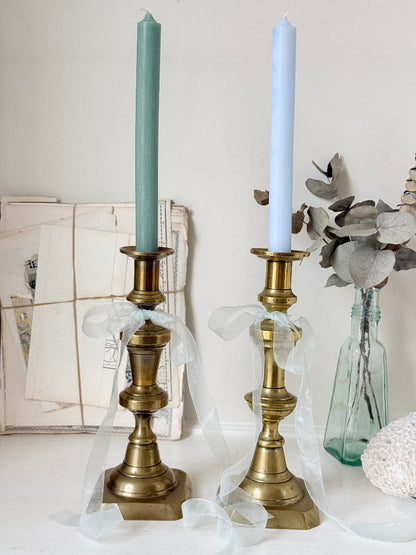 Pair of tall antique brass candlesticks with knopped columns and octagonal stepped bases holding blue and green tapers