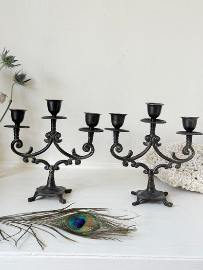 Pair of vintage brass three arm candelabra with scrolling arms and aged patina, photographed on a white surface