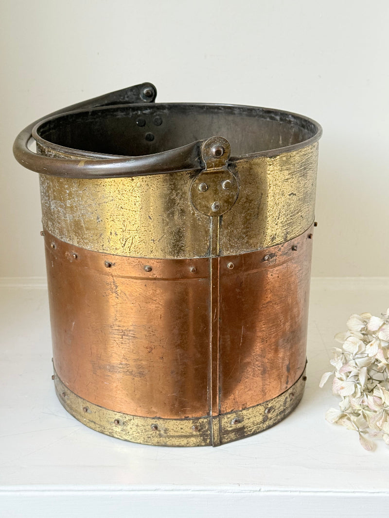 Vintage copper and brass metal bin with handle, photographed on a white surface.