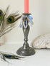 Antique pewter candlestick with baluster stem and aged patina styled with coral candle on white surface