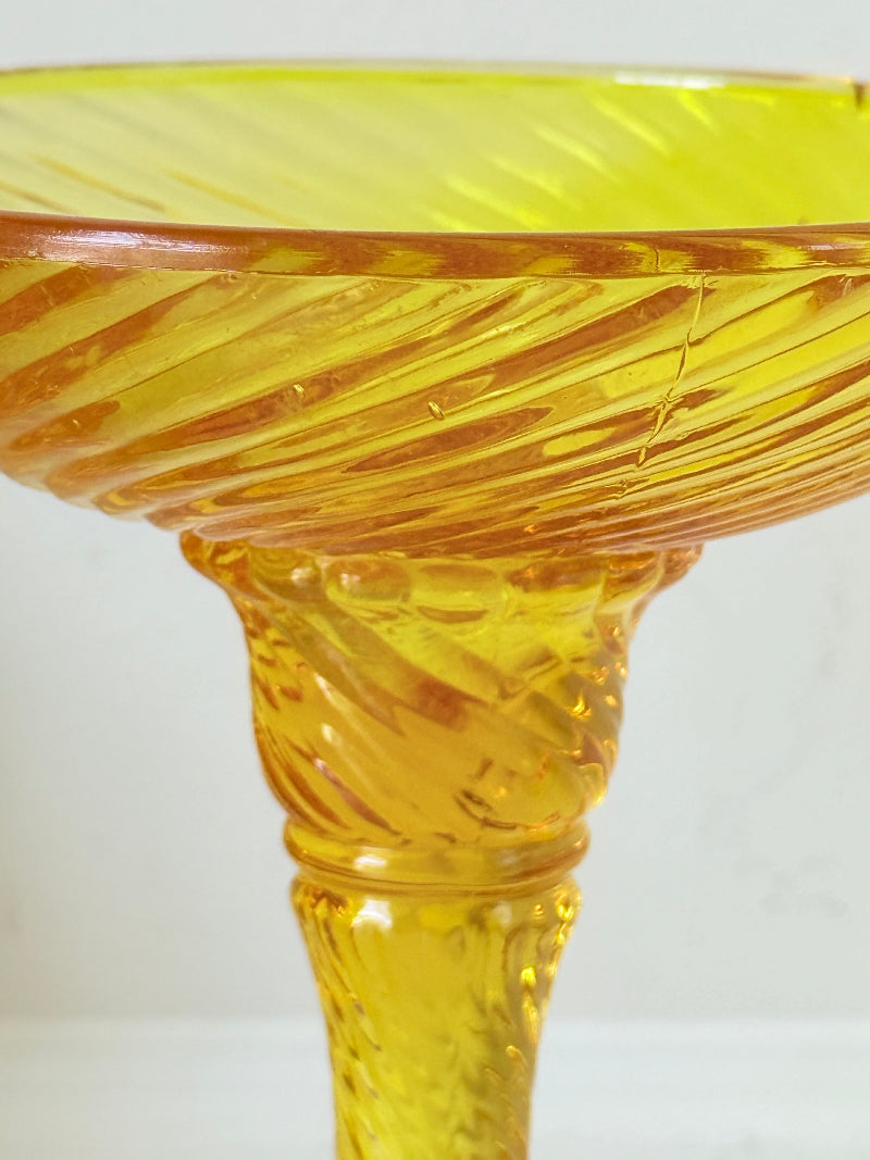 Amber pressed glass candle holder or compote with swirl design and pedestal base, photographed on a white background