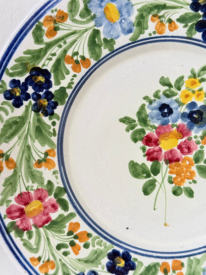 Vintage Italian majolica floral plate with blue green yellow and pink decoration photographed on a white surface