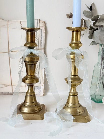 Pair of tall antique brass candlesticks with knopped columns and octagonal stepped bases holding blue and green tapers