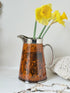 Antique Ridgways stoneware jug photographed on a white surface in amber treacle glaze with black Coaching Days and Coaching Ways scenes and silver lustre rim