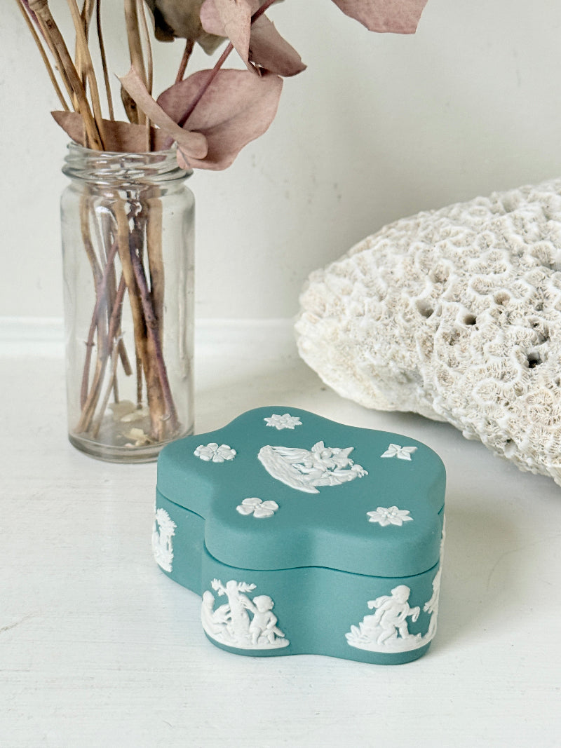 Vintage Wedgwood Jasperware teal green lidded trinket box in a quatrefoil shape, decorated with white neoclassical figures and florets, styled with dried stems.
