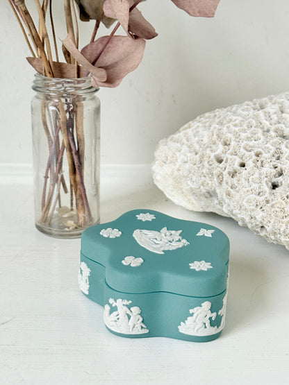 Vintage Wedgwood Jasperware teal green lidded trinket box in a quatrefoil shape, decorated with white neoclassical figures and florets, styled with dried stems.
