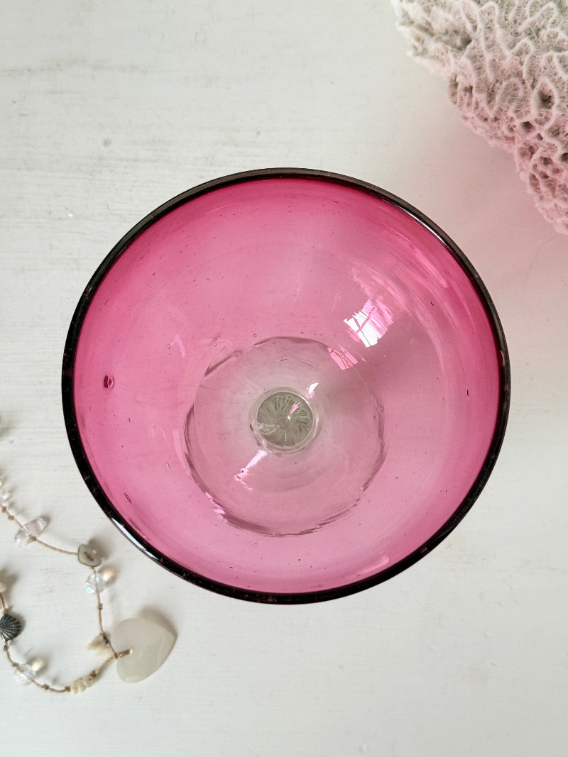 Vintage cranberry glass bonbon dish with clear stem and foot, photographed on a white surface
