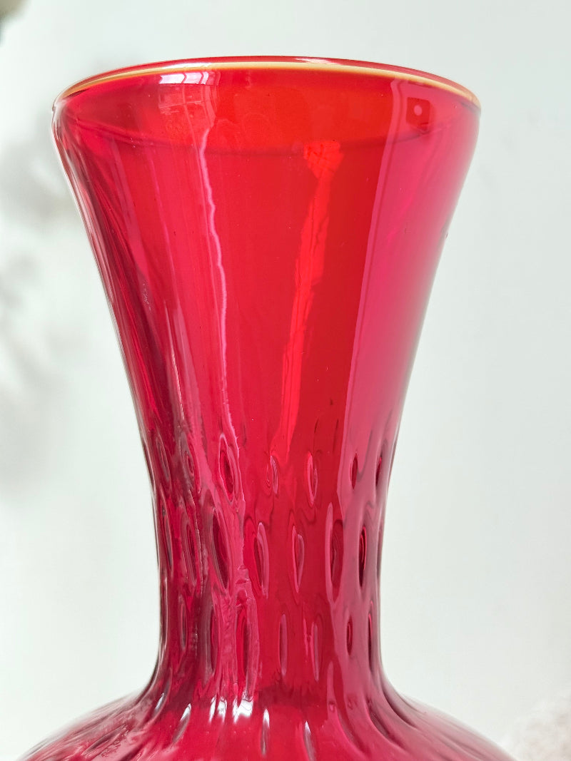 Italian red glass vase with strawberry textured surface, photographed on a white background.