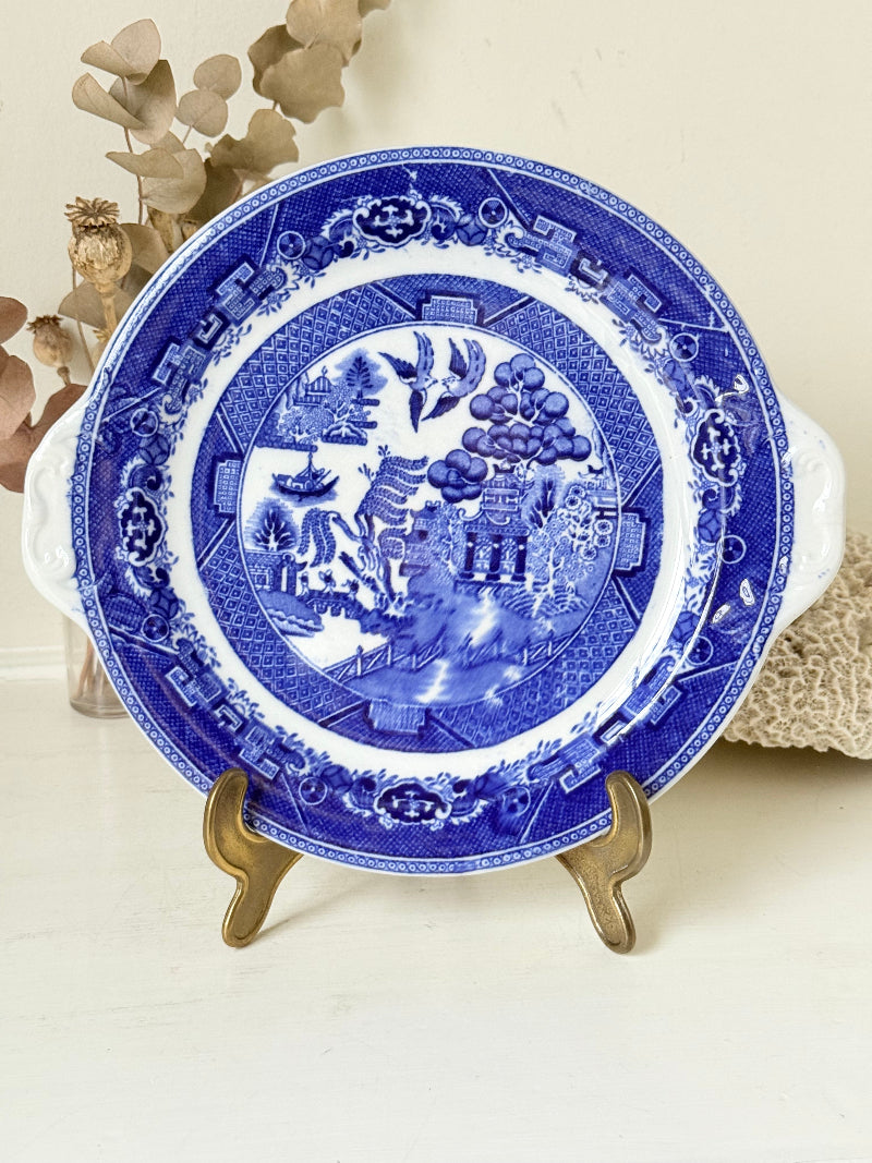 Blue Willow serving plate with scroll handled relief shown on a white surface.