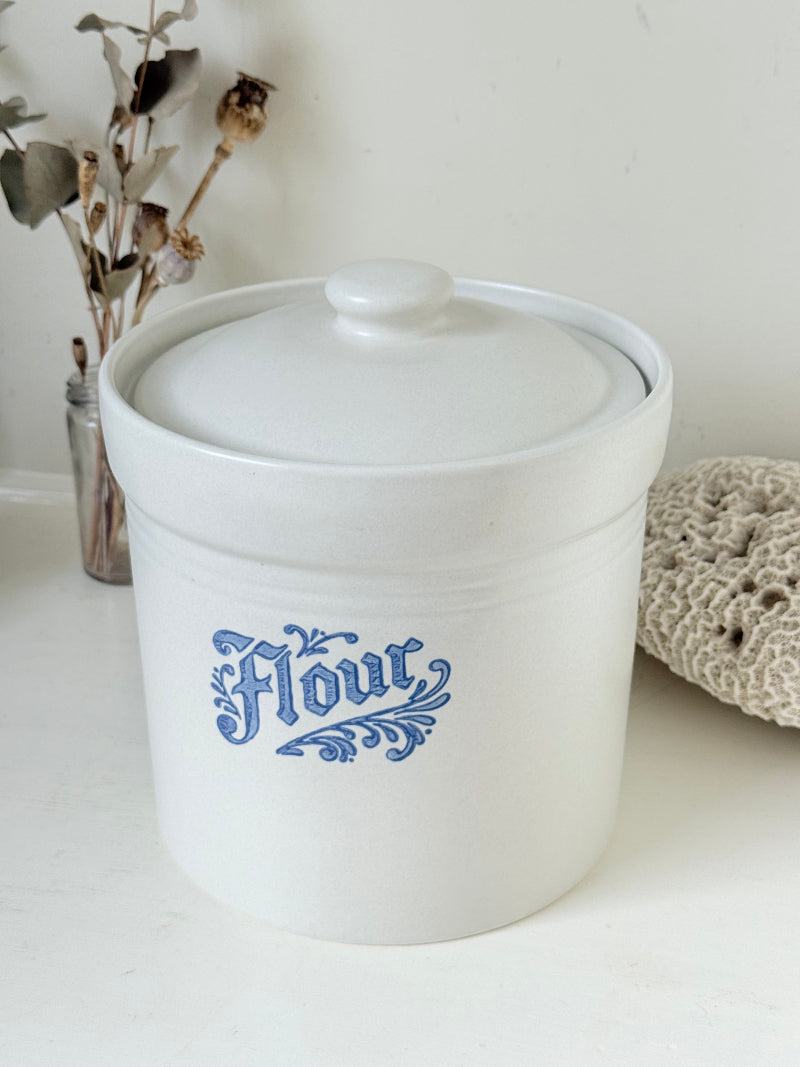 Pfaltzgraff Yorktowne stoneware flour pot with blue floral motif and lid, photographed on a white surface