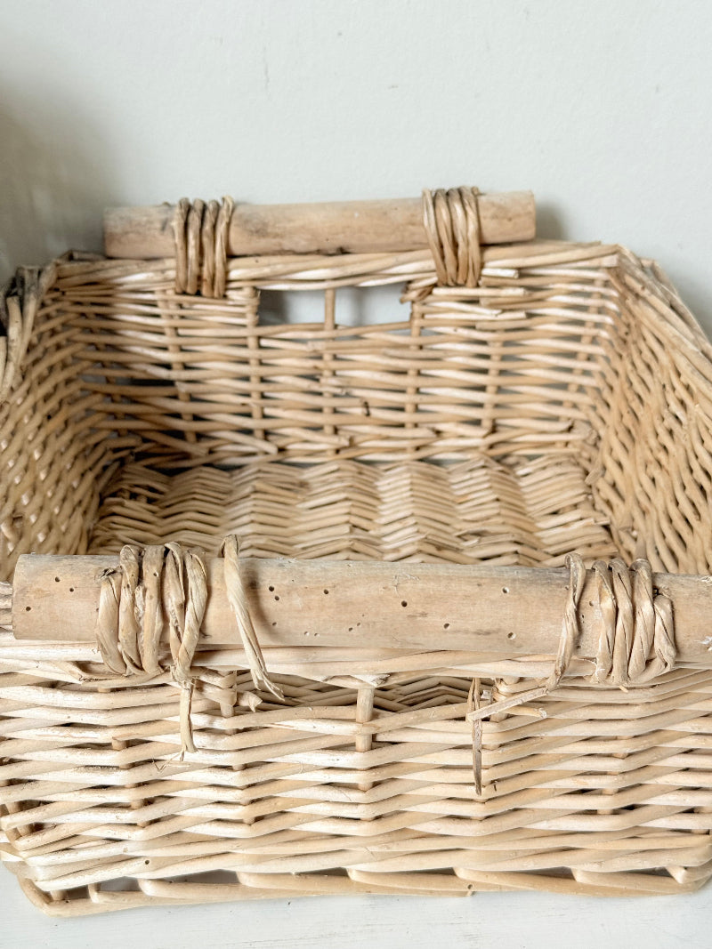 Set of three vintage woven willow baskets in natural tones photographed on a white surface