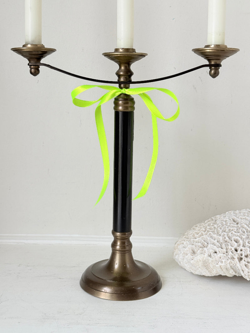 Vintage three arm candelabra in brass and ebonised metal with ivory taper candles styled on a white surface