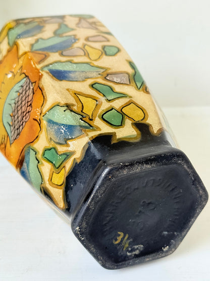 Art Deco Brentleigh Ware vase with hand painted floral design in orange, yellow, and teal on a black ground, photographed on a white surface