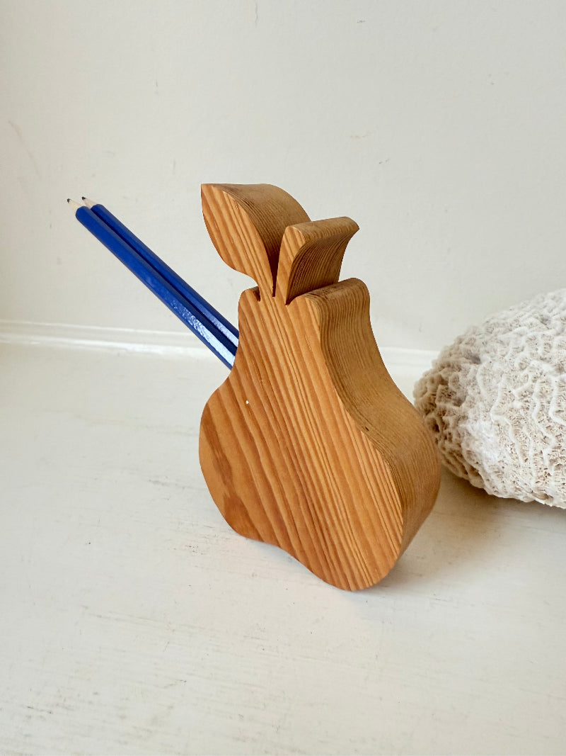 Vintage wooden pear sculpture in natural grain photographed on a white surface.