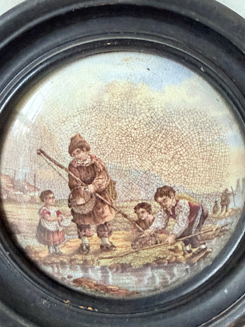 Antique Prattware framed ceramic lid with rural family scene photographed on a white surface.