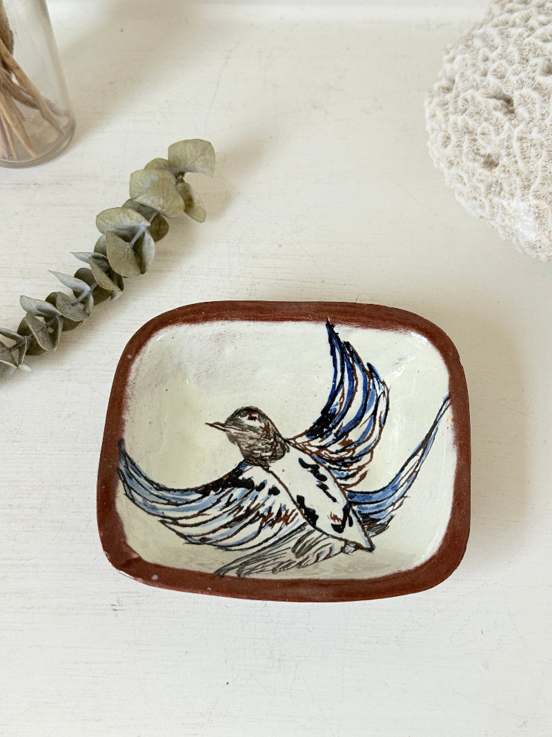 Vintage studio pottery soap dish with hand painted blue bird motif and terracotta rim, photographed on a white surface