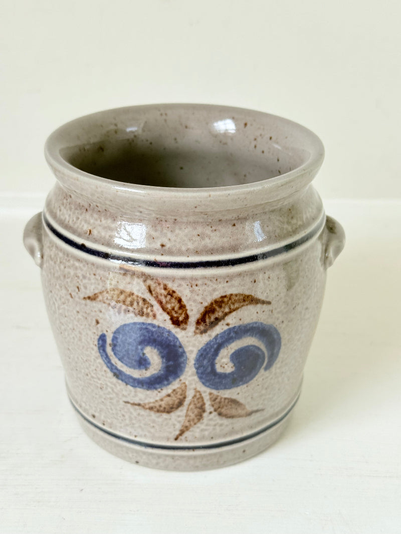 Vintage stoneware confit pot with blue and brown folk art design, photographed on a white surface