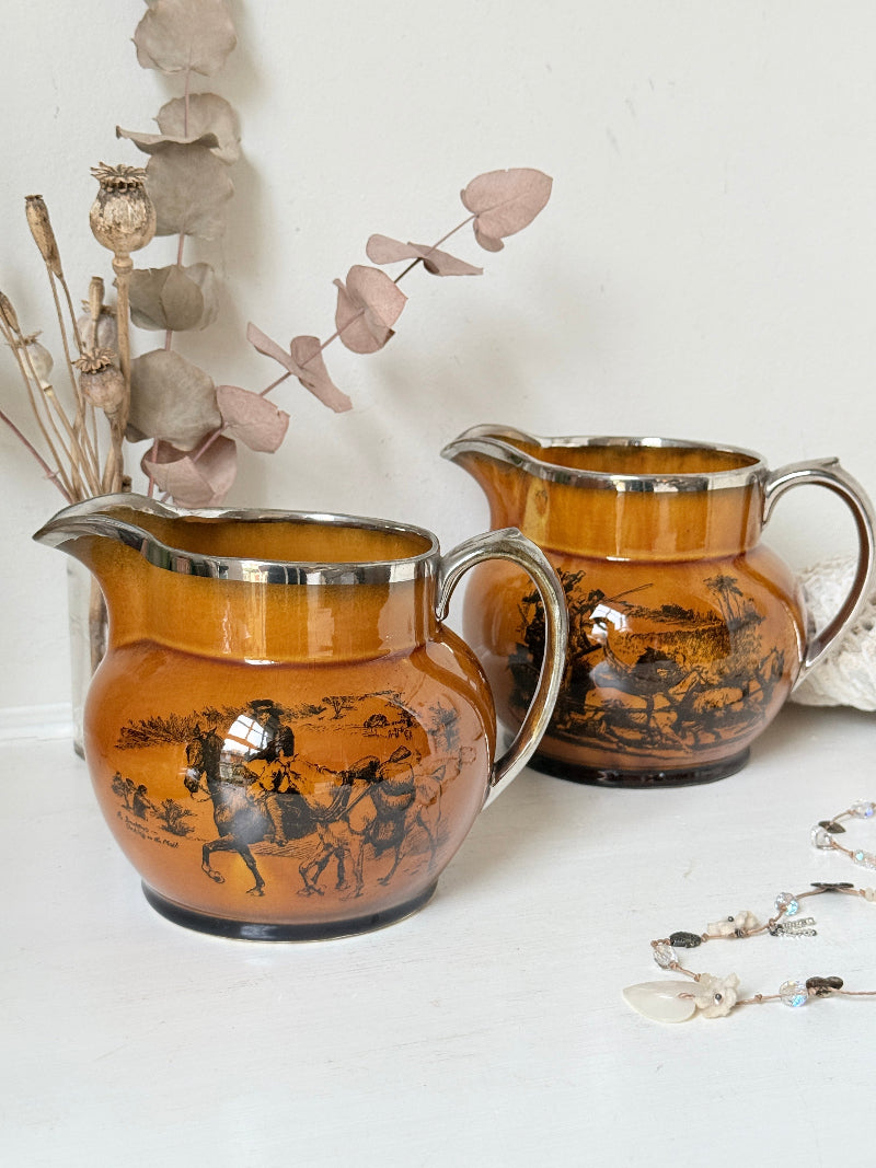 Pair of vintage Ridgways Coaching Days and Coaching Ways treacle jugs in amber brown glaze photographed on a white surface
